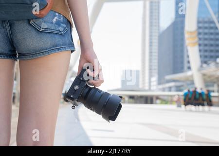 Nahaufnahme eines Reisekonzepts für weibliche Reisende mit Handkamera und Hintergrund von bangkok thailand. Stockfoto