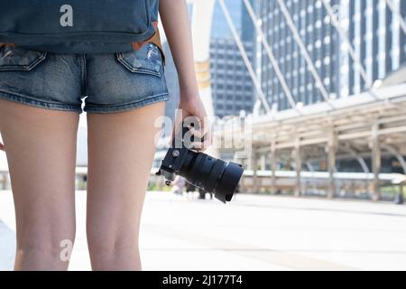 Nahaufnahme eines Reisekonzepts für weibliche Reisende mit Handkamera und Hintergrund von bangkok thailand. Stockfoto