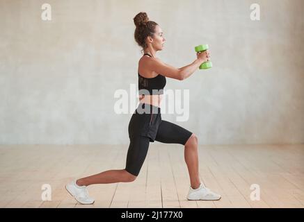 Horizontale Ganzkörper-Seitenansicht Aufnahme der modernen sportlichen yong erwachsenen kaukasischen Frau beim Training mit Hantel Stockfoto