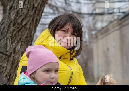 Mütter mit einer Tochter im Vorschulalter und einem Haustier in den Armen draußen. Ein fünfjähriges Mädchen, eine Frau mittleren Alters und ein Chihuahua-Hund. Familie. Schließen-U Stockfoto