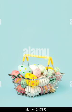 Frohe Ostern. Bunte ostereier in einem Warenkorb mit Kopierfläche auf blauem Hintergrund Stockfoto