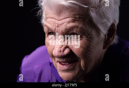 Porträt einer ernsthaften älteren Frau vor schwarzem Hintergrund Stockfoto