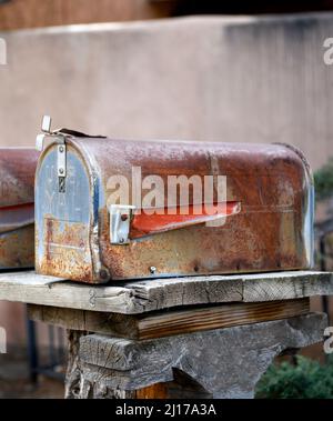 Eine Reihe rostiger Briefkästen vor historischen Wohnhäusern in Santa Fe, New Mexico. Stockfoto