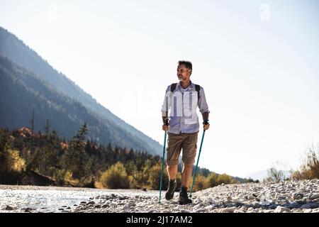 Österreich, Alpen, Mann auf einer Wanderung zu Fuß auf Kieselsteinen entlang eines Baches Stockfoto