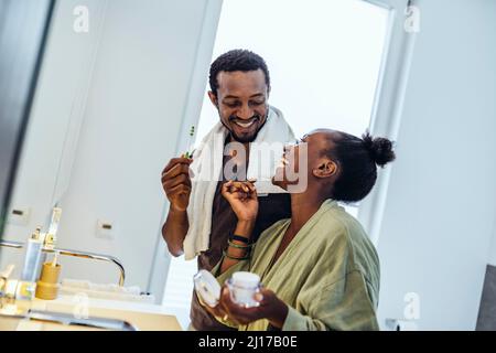 Glückliche Frau im Badezimmer zu Hause im Gespräch mit dem Mann Stockfoto