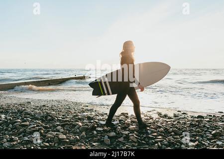 Surfer mit Surfbrett zu Fuß am Strand. Stockfoto