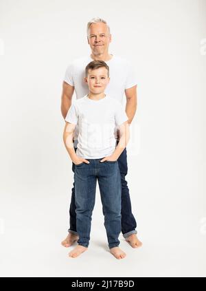 Junge mit Händen in den Taschen, die vor dem Vater im Studio stehen Stockfoto