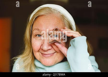 Ältere Frau schaut durch einen sternförmigen Ausstecher Stockfoto