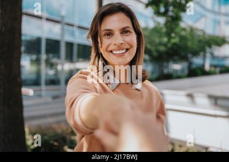 Glückliche Frau, die sich im Büropark die Hände schüttelt Stockfoto