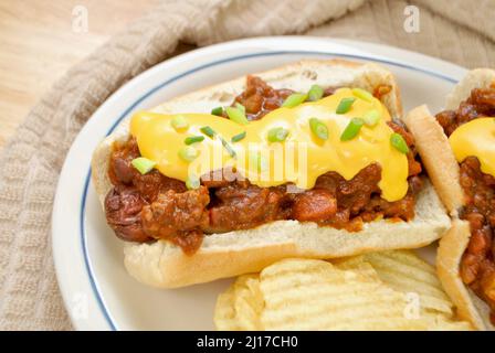 Beladen Chilli Dog mit Cheddar-Käse und Scallion serviert mit gewellten Kartoffelchips Stockfoto