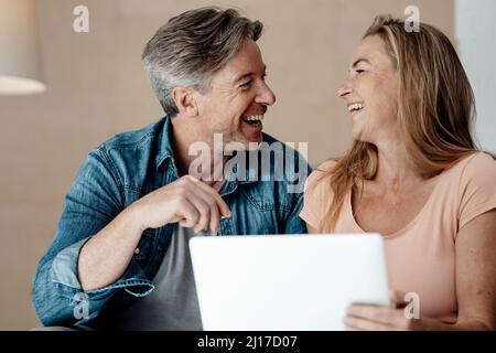 Fröhliche Frau und Mann sitzen mit Laptop zu Hause Stockfoto