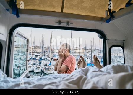 Mann, der das Gesicht mit den Händen von Wohnmobil bedeckt Stockfoto