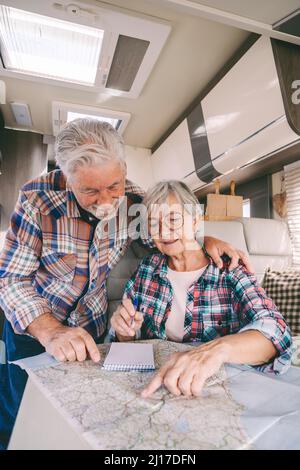 Lächelndes Seniorenpaar, das im Wohnmobil über die Führerkarte spricht Stockfoto