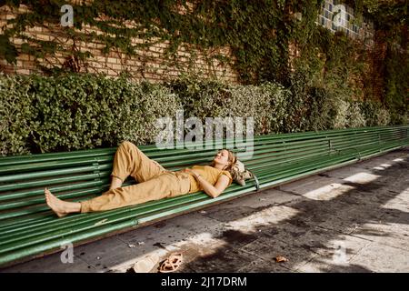 Frau, die sich auf der Bank im öffentlichen Park ausruht Stockfoto