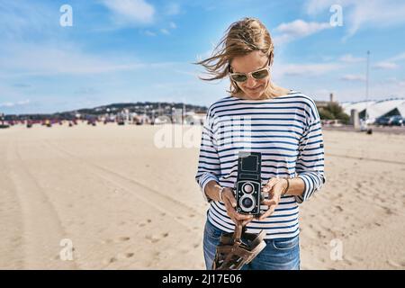 Tourist mit Vintage-Kamera, die an sonnigen Tagen am Strand steht Stockfoto