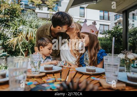 Eltern küssen sich von Kindern auf der Party im Hinterhof Stockfoto