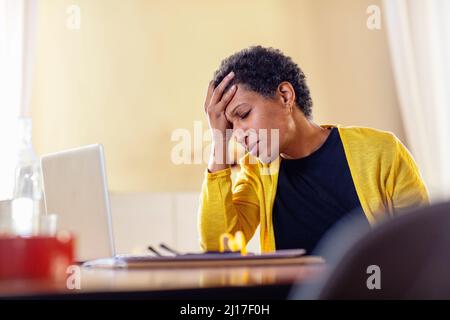 Gestresste Geschäftsfrau mit Laptop zu Hause Stockfoto