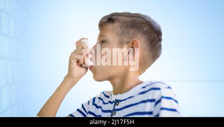 Kaukasischer Junge mit einem Asthma-Inhalator gegen Ziegelwand und blauen Hintergrund Stockfoto