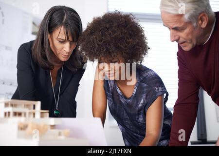 Wir haben unseren Prototyp noch aufrüstet. Aufnahme von drei Architekten, die am Arbeitsplatz ein Architekturmodell diskutieren. Stockfoto