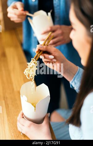 Frau, die in der Küche Nudeln mit Essstäbchen isst Stockfoto