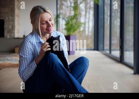 Lächelnde Frau mit Katze zu Hause Stockfoto