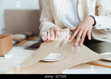 Craftswoman Verpackung Keramikplatte in Geschenkpapier für den Versand Stockfoto
