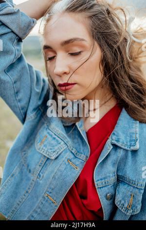 Junge Frau mit geschlossenen Augen in Denim-Jacke Stockfoto