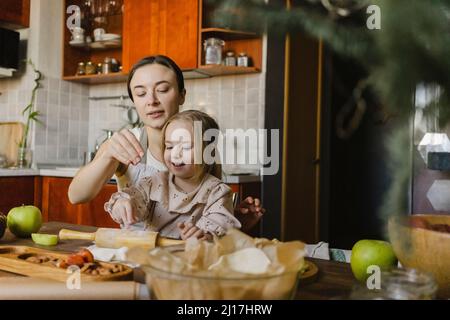 Mutter und Tochter streuen Mehl in der Küche zu Hause Stockfoto