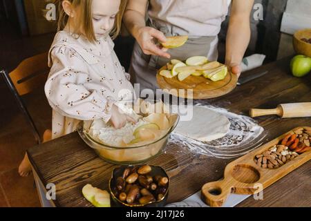 Tochter und Mutter bereiten Apfelkuchen in der Küche zu Hause Stockfoto