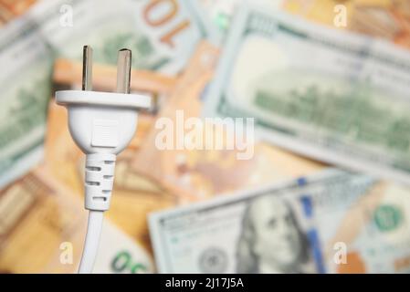 Elektrischer Stecker auf einem Hintergrund von Banknoten. Konzepte der Erhöhung der Energiepreise, der Stromkosten und des Stromverbrauchs. Stockfoto