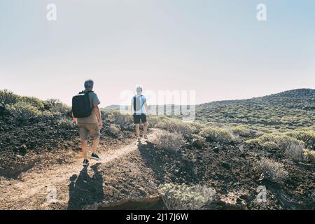 Ältere Männer und Frauen, die Rucksack tragen, gehen auf dem Fußweg Stockfoto