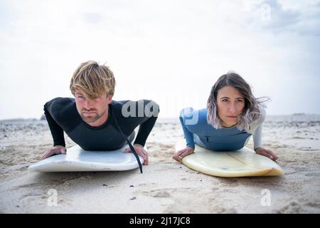 Mann und Frau liegen am Strand auf dem Surfbrett Stockfoto