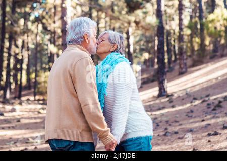 Liebevolles Seniorenpaar küsst sich gegenseitig im Wald Stockfoto