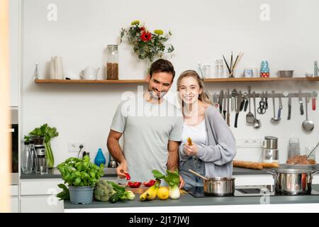 Glückliche Freundin und Freund, die in der Küche Essen zubereiten Stockfoto