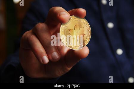 Maple Leaf kanadische Goldmünze in Hand abstraktes Konzept. Stockfoto