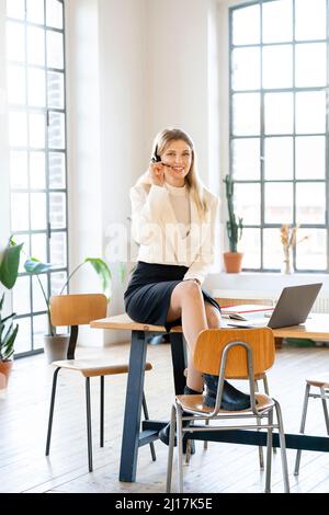 Lächelnde Geschäftsfrau mit Headset, die im Heimbüro arbeitet Stockfoto