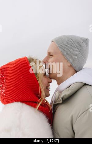 Lächelnder Mann mit Strickmütze, der im Winter mit einer blonden Freundin steht Stockfoto