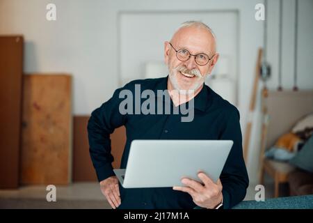 Glücklicher Mann mit Laptop im Büro Stockfoto