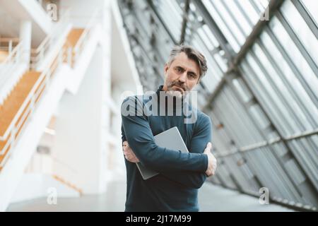 Ernsthafter Geschäftsmann mit Tablet-Computer am Arbeitsplatz Stockfoto