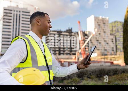 Lächelnder Architekt mit Tablet-PC auf der Baustelle Stockfoto