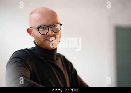Lächelnder, kahlköpfiger Mann, der im Büro eine Brille trug Stockfoto