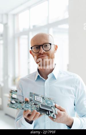 Geschäftsmann, der mit einer Leiterplatte im Büro steht Stockfoto