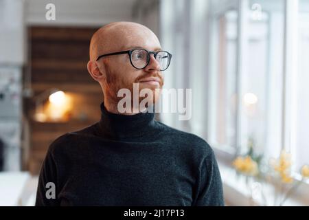 Kahlköpfiger Mann, der im Büro eine Brille trug Stockfoto