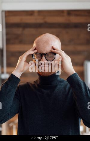 Frustrierter junger Geschäftsmann mit geschlossenen Augen im Büro Stockfoto