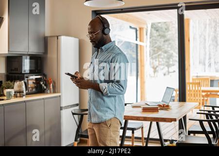 Mann mit Smartphone, der zu Hause in der Küche steht Stockfoto