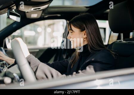 Lächelnde Geschäftsfrau mit Bedienfeld des Elektroautos Stockfoto