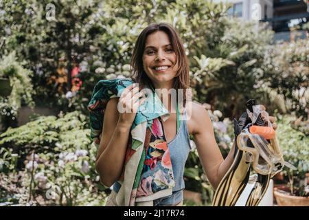 Glückliche Frau, die im Garten ein Handtuch mit Taucherflossen und Schwimmbrille hält Stockfoto