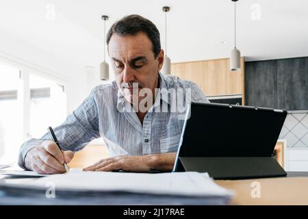 Mann, der Musiknoten schreibt, sitzt am Tisch Stockfoto