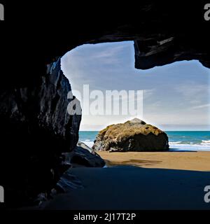 Blick auf das Meer von einer der vielen Sandboden-Höhlen an der Penbryn-Küste in Cardigan Bay Wales, Großbritannien Stockfoto