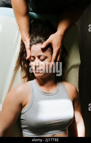 Physiotherapeut gibt Kopfmassage für die Frau, die mit geschlossenen Augen liegt Stockfoto